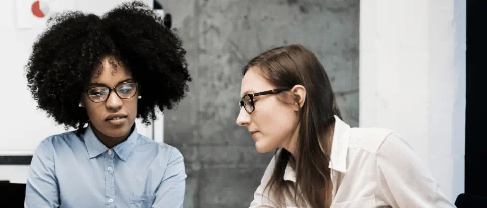 Two women are looking at a computer screen together discussing the contents