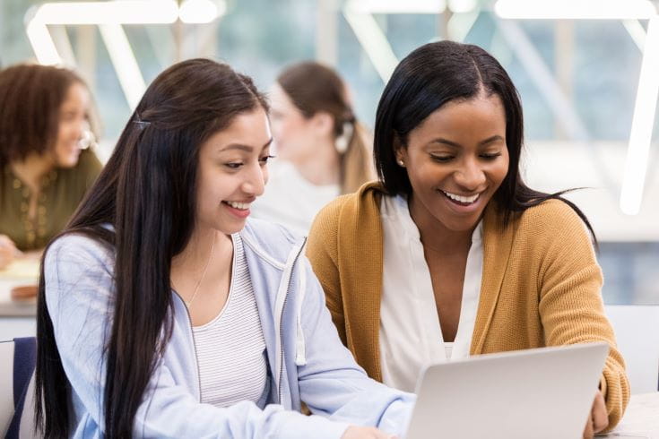 Two-Females-Sat-At-Table-Looking-At-A-Laptop